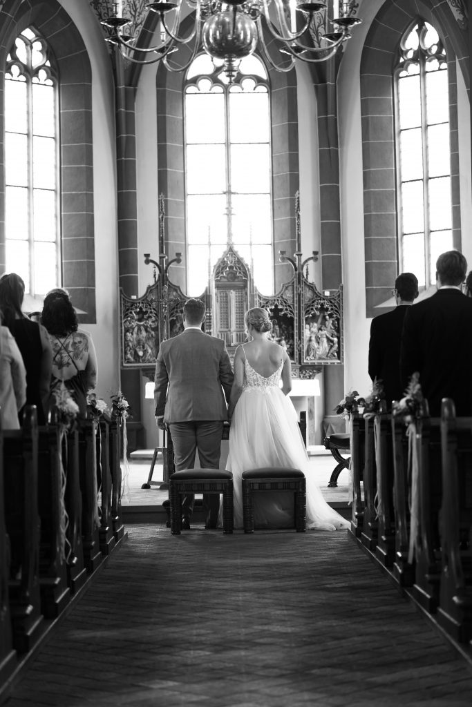 Schwarzwei&szlig; Hochzeitsfotografie der kirchlichen Trauung in der Kirche von Hanau in der N&auml;he von Frankfurt am Main. Die Braut tr&auml;gt ein sch&ouml;nes Brautkleid und der Br&auml;utigam einen sch&ouml;nen Anzug. Die Kirche fand in Hanau in der N&auml;he von Frankfurt am Main statt