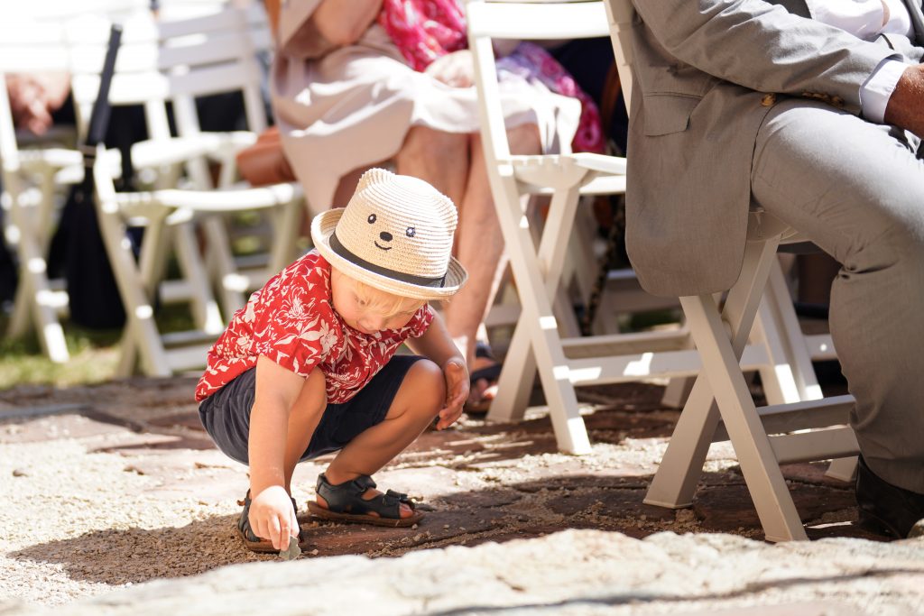 Hochzeitsfotografie von der standesamtlichen Trauung eines Brautpaars in schickem Brautkleid und Anzug im Rahmen einer Hochzeit. Die Sonne scheint in der Natur auf der Burg von Kronberg im Taunus in der N&auml;he von Frankfurt am Main. Sie tr&auml;gt ihren Brautstrau&szlig; in der Hand. Neben ihnen sitzen ihre Trauzeugen. Die Standesbeamte sitzt vor ihnen. Sie haben einen sch&ouml;nen Ausblick auf die Altstadt und den Taunus. Hinter ihnen sitzen ihre Familien.
