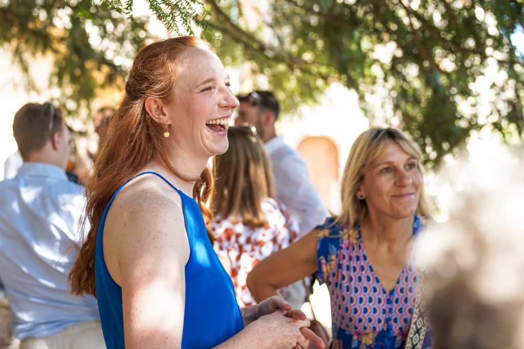 Hochzeitsfotografie von der standesamtlichen Trauung eines Brautpaars in schickem Brautkleid und Anzug im Rahmen einer Hochzeit. Die Sonne scheint in der Natur auf der Burg von Kronberg im Taunus in der N&auml;he von Frankfurt am Main. Sie steckt ihrem Mann den Ehering an die Hand und der steckt ihr den Ring an ihre Hand. Neben ihnen sitzen ihre Trauzeugen. Die Standesbeamte sitzt vor ihnen. Sie haben einen sch&ouml;nen Ausblick auf die Altstadt und den Taunus. Hinter ihnen sitzen ihre Familien. Sie haben viel Spa&szlig; auf ihrer Hochzeitsfeier und Party.