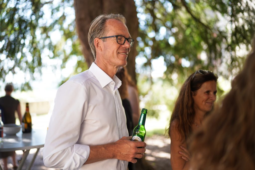 Hochzeitsfotografie von der standesamtlichen Trauung eines Brautpaars in schickem Brautkleid und Anzug im Rahmen einer Hochzeit. Die Sonne scheint in der Natur auf der Burg von Kronberg im Taunus in der N&auml;he von Frankfurt am Main. Sie steckt ihrem Mann den Ehering an die Hand und der steckt ihr den Ring an ihre Hand. Neben ihnen sitzen ihre Trauzeugen. Die Standesbeamte sitzt vor ihnen. Sie haben einen sch&ouml;nen Ausblick auf die Altstadt und den Taunus. Hinter ihnen sitzen ihre Familien. Sie haben viel Spa&szlig; auf ihrer Hochzeitsfeier und Party.
