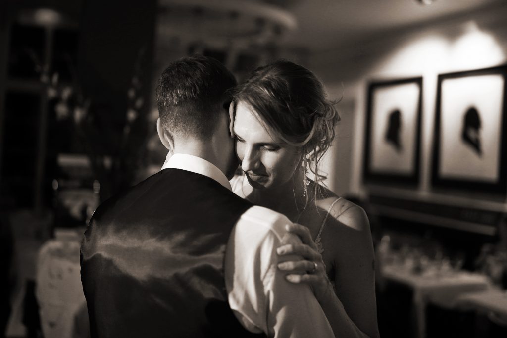 Schwarzwei&szlig; Hochzeitsfotografie vom Hochzeitstanz eines Brautpaars in schickem Brautkleid und Anzug im Rahmen einer Hochzeit. Sie tanzen in Aschaffenburg in der N&auml;he von Frankfurt am Main stehen