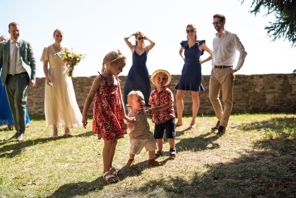 Hochzeitsfotografie von der standesamtlichen Trauung eines Brautpaars in schickem Brautkleid und Anzug im Rahmen einer Hochzeit. Die Sonne scheint in der Natur auf der Burg von Kronberg im Taunus in der N&auml;he von Frankfurt am Main. Sie steckt ihrem Mann den Ehering an die Hand und der steckt ihr den Ring an ihre Hand. Neben ihnen sitzen ihre Trauzeugen. Die Standesbeamte sitzt vor ihnen. Sie haben einen sch&ouml;nen Ausblick auf die Altstadt und den Taunus. Hinter ihnen sitzen ihre Familien. Sie haben viel Spa&szlig; auf ihrer Hochzeitsfeier und Party.