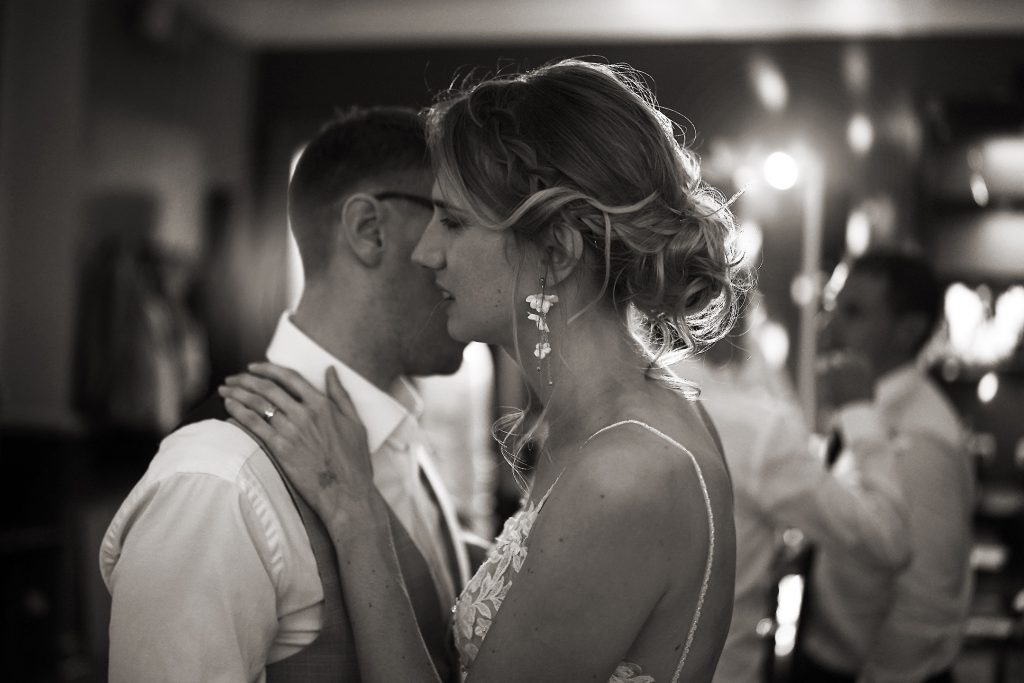 Schwarzwei&szlig; Hochzeitsfotografie vom Hochzeitstanz eines Brautpaars in schickem Brautkleid und Anzug im Rahmen einer Hochzeit. Sie tanzen in Aschaffenburg in der N&auml;he von Frankfurt am Main stehen