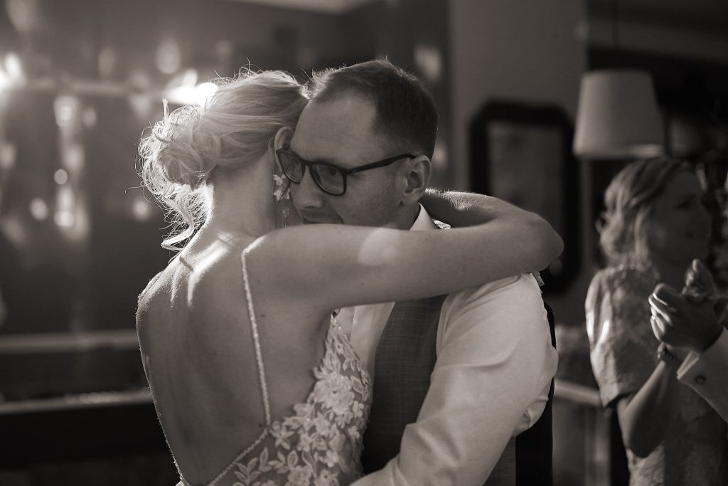 Schwarzwei&szlig; Hochzeitsfotografie vom Hochzeitstanz eines Brautpaars in schickem Brautkleid und Anzug im Rahmen einer Hochzeit. Sie tanzen in Aschaffenburg in der N&auml;he von Frankfurt am Main stehen