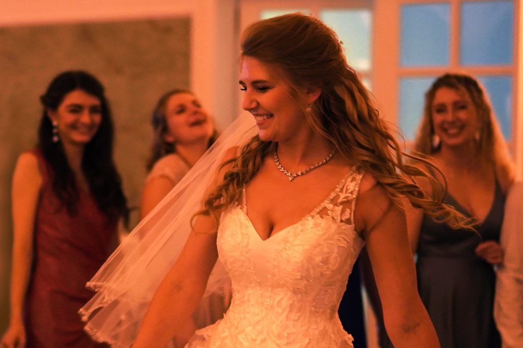 Hochzeitsfotografie von Braut in schickem Brautkleid im Rahmen einer Hochzeit in der N&auml;he von Frankfurt am Main. Die Braut beginnt mit dem Hochzeitstanz vor ihren Trauzeuginnen. Sie genie&szlig;t ihren Hochzeitstag