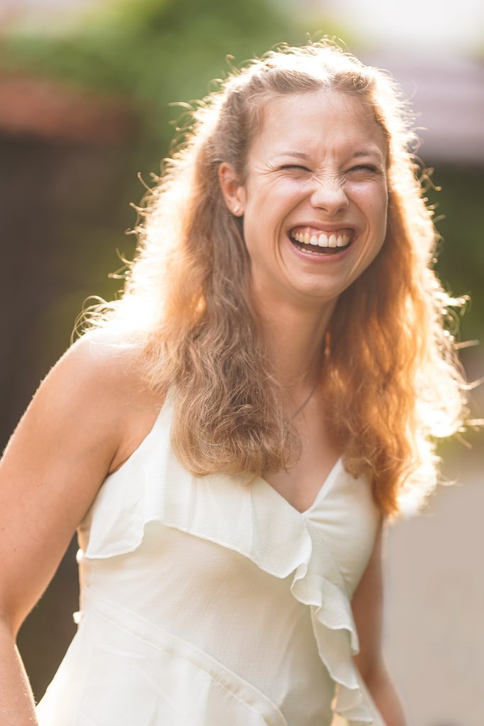 Fotografie-Hochzeit-Trauzäugin-Sonnenschein-Augen-Licht-Hanau-Frankfurt-Fashion-Mode-Locken Fotografie einer jungen attraktiven Frau im Rahmen eines Fotoshootings einer Hochzeit als Trauzeugin. Die Sonne scheint in ihre Augen und ihre Locken leuchten. Sie steht in der Natur von Hanau in der Nähe von Frankfurt am Main. Sie trägt ein schickes Kleid