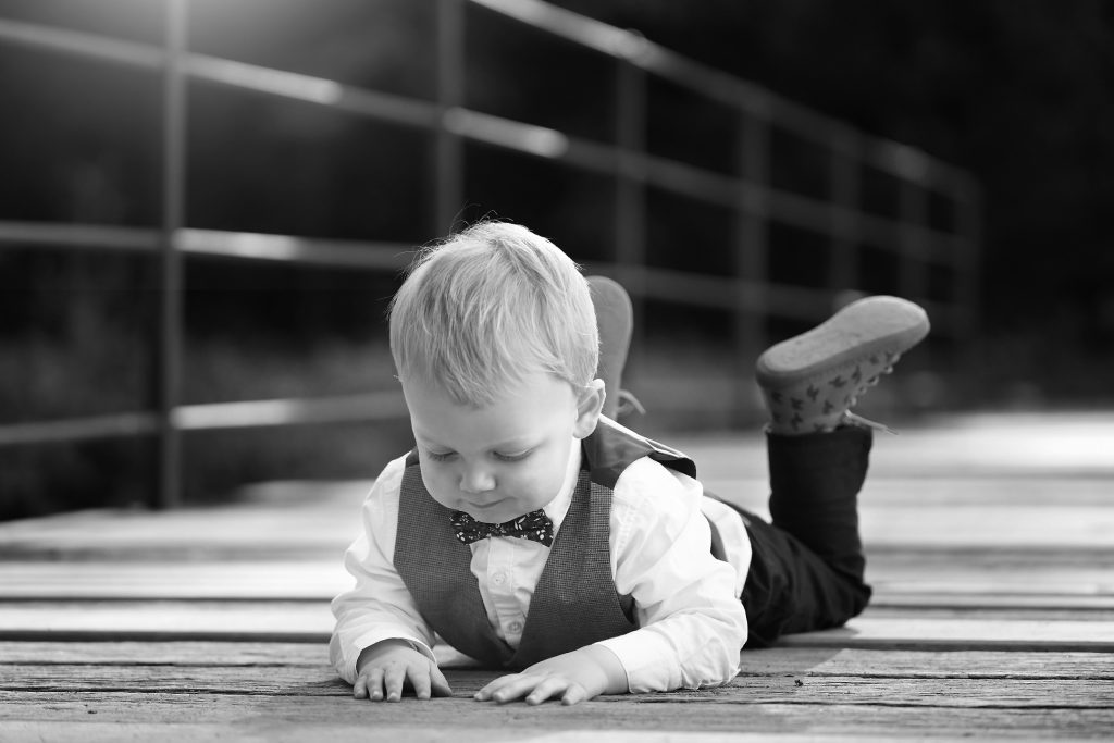 Familienfotografie-Schwarzweiß-Kinder-glücklich-Natur-Brücke Schwarzweiß Familienfotografie von Kind in Natur auf einer Brücke im Sonnenschein
