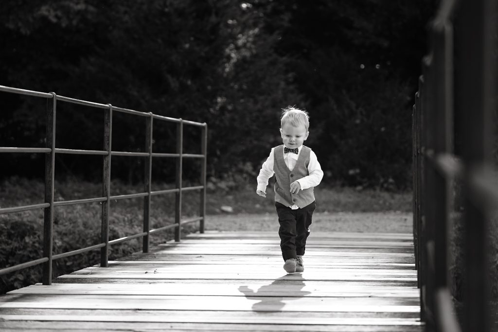 Familienfotografie-Kind-glücklich-Natur-Brücke-Sonne-schwarzweiß Familienfotografie von Kind in in Natur auf einer Brücke im Sonnenschein in schwarzweiß