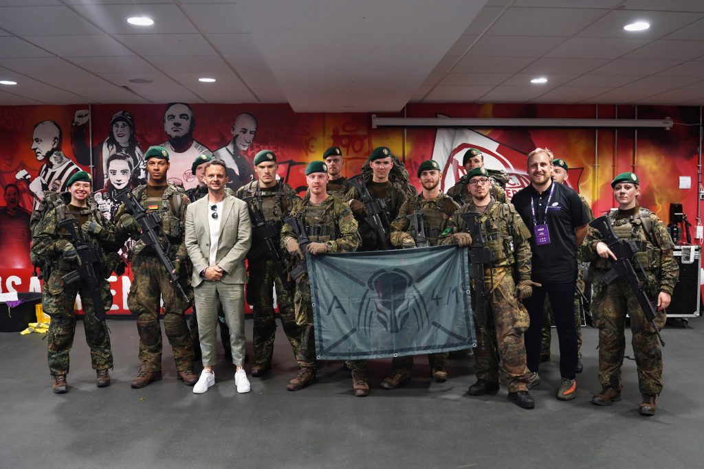 Event-Fotografie von Bundeswehr-Soldaten beim Stadion am Biederer Berg in Offenbach in der N&auml;he von Frankfurt am Main im Rahmen des Salute The Troops-Spiels von Frankfurt Galaxy. Die Soldatin tragen ein G36 von der Firma Heckler und Koch. Sie posieren zusammen mit dem CEO von Frankfurt Galaxy Eric Reutemann